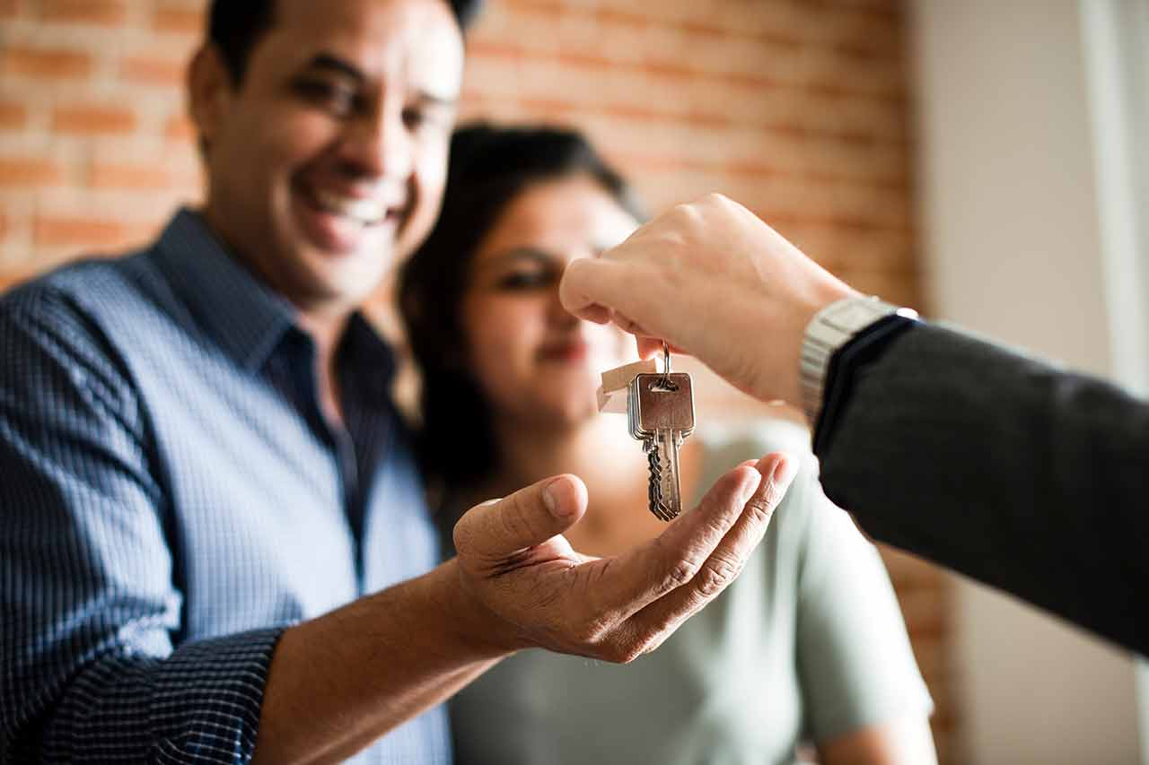 A couple receiving keys to their second home from their mortgage loan officer after closing on the home.
