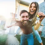 Happy couple celebrating in front of their new home while holding house keys