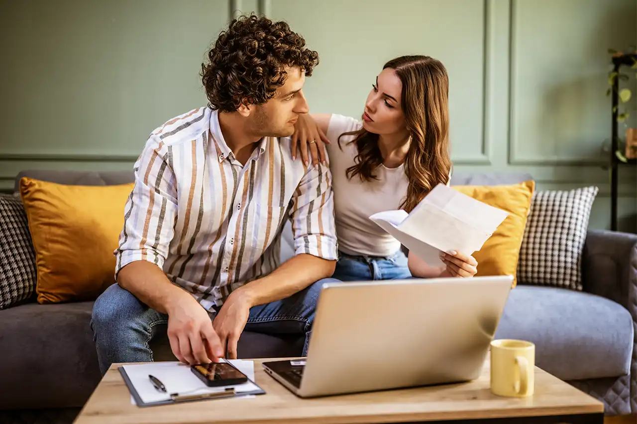 Couple reviewing mortgage documents together at home with a laptop